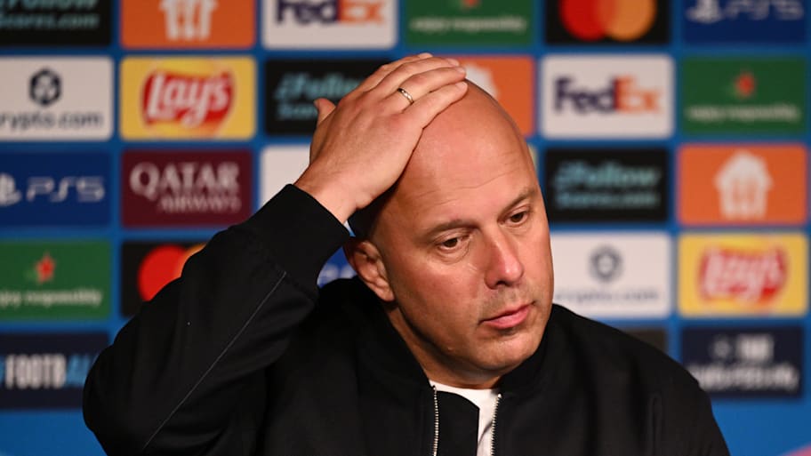 Arne Slot rubbing his bald head.