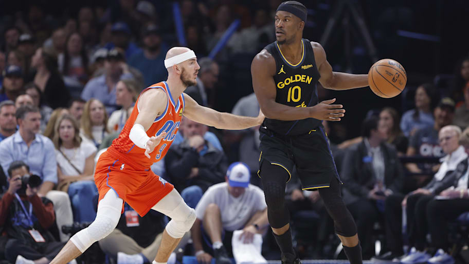 Warriors forward Jimmy Butler moves the ball across the court as Thunder guard Alex Caruso defends.