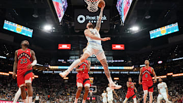 Apr 13, 2025; San Antonio, Texas, USA; San Antonio Spurs forward Sandro Mamukelashvili (54) drives to the basket past Toronto Raptors guards Jamal Shead (23), AJ Lawson (0), and forward Jonathan Mogbo (2) during the second half at Frost Bank Center. Mandatory Credit: Scott Wachter-Imagn Images