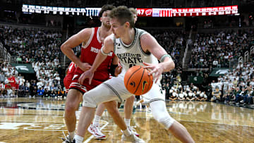  Mar 2, 2025; East Lansing, Michigan, USA;  Michigan State Spartans forward Jaxon Kohler (0) moves the ball down the baseline against Wisconsin Badgers forward Carter Gilmore (7) during the second half at Jack Breslin Student Events Center. Mandatory Credit: Dale Young-Imagn Images