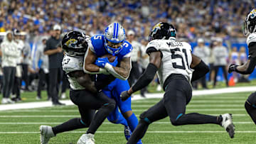 Nov 17, 2024; Detroit, Michigan, USA; Detroit Lions running back David Montgomery (5) runs with the ball and is tackles by Jacksonville Jaguars linebacker Foyesade Oluokun (23) and linebacker Ventrell Miller (51) during the first half at Ford Field. Mandatory Credit: David Reginek-Imagn Images
