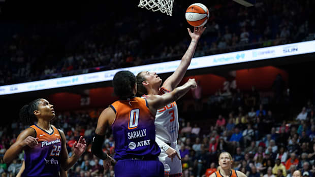 Connecticut Sun guard Marina Mabrey scores a layup, wearing a white jersey with orange lettering. 
