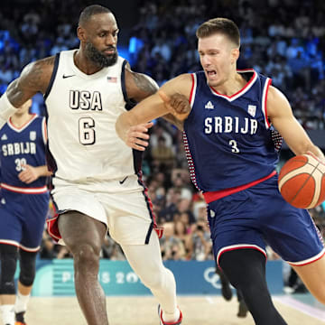 Aug 8, 2024; Paris, France; Serbia centre Filip Petrusev (3) drives to the basket while defended by United States guard LeBron James (6) during the first half in a men's basketball semifinal game during the Paris 2024 Olympic Summer Games at Accor Arena. Mandatory Credit: Kyle Terada-Imagn Images