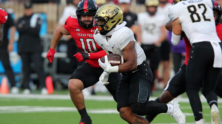 Nov 18, 2023; Lubbock, Texas, USA;  Central Florida Knights running back RJ Harvey (7) rushes against Texas Tech Red Raiders defensive back Jacob Rodriguez (10) in the first half at Jones AT&T Stadium and Cody Campbell Field. Mandatory Credit: Michael C. Johnson-USA TODAY Sports