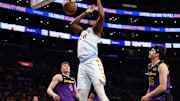 Jan 13, 2025; Los Angeles, California, USA;  San Antonio Spurs center Charles Bassey (28) dunks a ball against Los Angeles Lakers guard Dalton Knecht (4) and guard Austin Reaves (15) during the second half at Crypto.com Arena. Mandatory Credit: Kiyoshi Mio-Imagn Images
