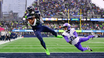 Dec 22, 2024; Seattle, Washington, USA; Seattle Seahawks wide receiver DK Metcalf (14) catches a pass for a touchdown while defended by Minnesota Vikings cornerback Stephon Gilmore (2) during the first half at Lumen Field.