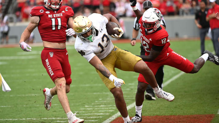 Sep 9, 2023; Raleigh, North Carolina, USA; Notre Dame Fighting Irish tight end Holden Staes (13) is knocked out of bounds by North Carolina State Wolfpack safety Devan Boykin (12) after a catch during the second half at Carter-Finley Stadium. 