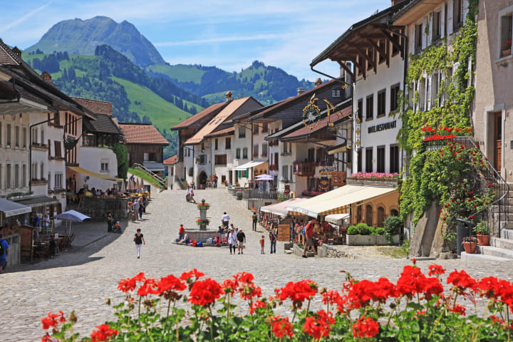 Houses lining the street of Gruyères, Switzerland, with mountains in the background