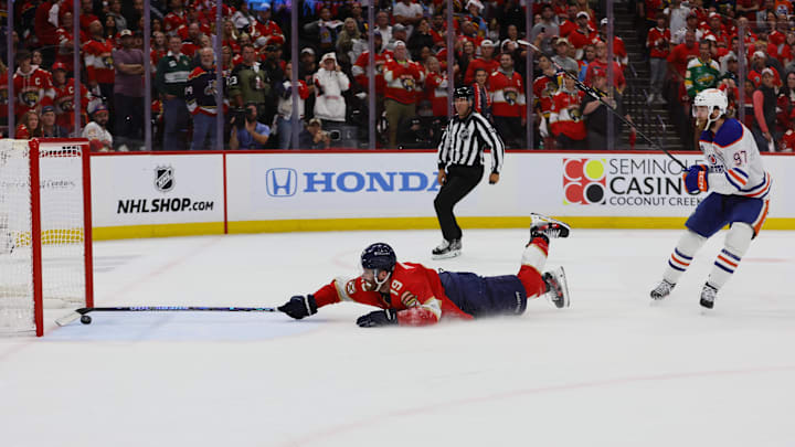 Jun 18, 2024; Sunrise, Florida, USA; Florida Panthers forward Matthew Tkachuk (19) reaches for the puck on an empty net attempt on goal by Edmonton Oilers forward Connor McDavid (97) during the third period in game five of the 2024 Stanley Cup Final at Amerant Bank Arena. Mandatory Credit: Sam Navarro-Imagn Images
