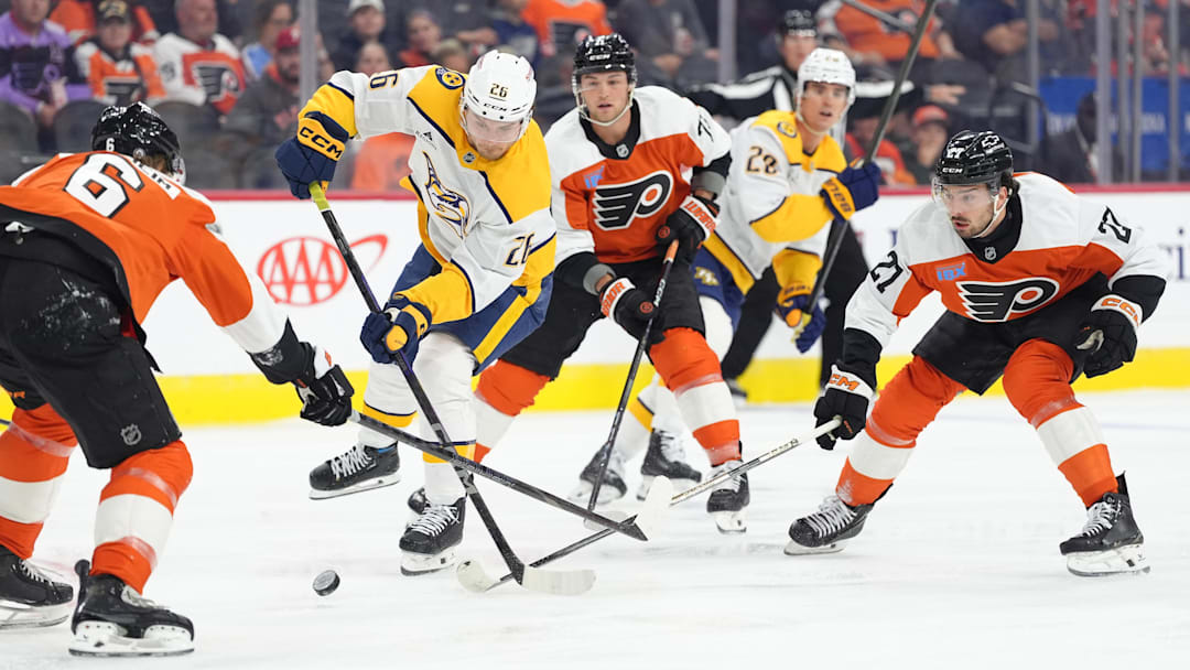 Mar 31, 2025; Philadelphia, Pennsylvania, USA; Nashville Predators left wing Kieffer Bellows (26) reaches for the puck against Philadelphia Flyers left wing Noah Cates (27) in the first period at Wells Fargo Center. 