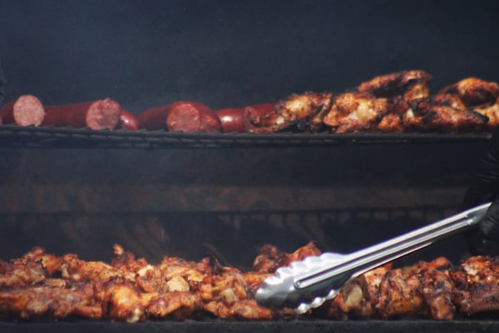 Sausage and chicken are on the grill near the concession stand. 