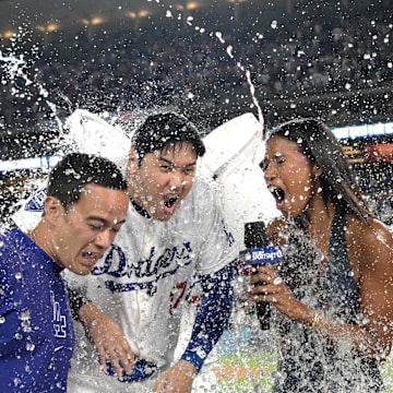 Aug 23, 2024; Los Angeles, California, USA;  Los Angeles Dodgers designated hitter Shohei Ohtani (17), center gets a cooler of ice water dumped on his head after hitting a grand slam walk off home run for his 40th of the season in the ninth inning against the Tampa Bay Rays at Dodger Stadium. At left is translator Will Ireton and right is Sports Net LA reporter Kirsten Watson. Mandatory Credit: Jayne Kamin-Oncea-Imagn Images