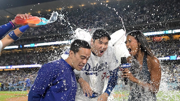 Aug 23, 2024; Los Angeles, California, USA;  Los Angeles Dodgers designated hitter Shohei Ohtani (17), center gets a cooler of ice water dumped on his head after hitting a grand slam walk off home run for his 40th of the season in the ninth inning against the Tampa Bay Rays at Dodger Stadium. At left is translator Will Ireton and right is Sports Net LA reporter Kirsten Watson. Mandatory Credit: Jayne Kamin-Oncea-Imagn Images