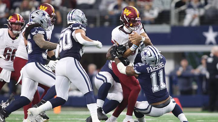 Jan 5, 2025; Arlington, Texas, USA; Washington Commanders quarterback Jayden Daniels (5) is gang tackled by the Dallas Cowboys defense during the second quarter at AT&T Stadium. Mandatory Credit: Tim Heitman-Imagn Images