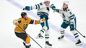 Oct 26, 2024; Las Vegas, Nevada, USA; San Jose Sharks defenseman Jack Thompson (26) bats down the puck between Vegas Golden Knights left wing Tanner Pearson (70) and San Jose Sharks defenseman Henry Thrun (3) during the third period at T-Mobile Arena. Mandatory Credit: Stephen R. Sylvanie-Imagn Images