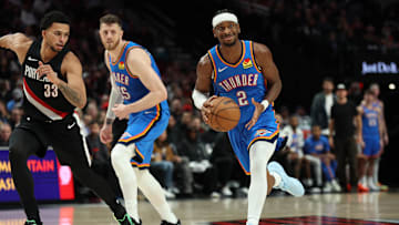 Nov 5, 2025; Portland, Oregon, USA;  Oklahoma City Thunder guard Shai Gilgeous-Alexander (2) dribbles the ball past Portland Trail Blazers forward Toumani Camara (33) as teammate Thunder’s center/forward Isaiah Hartenstein (55) watches during the first half at Moda Center. Mandatory Credit: Jaime Valdez-Imagn Images

