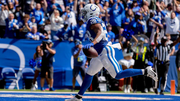 Colts running back Jonathan Taylor (blue jersey; white helmet/pants) runs in a touchdown in front of a home crowd. 