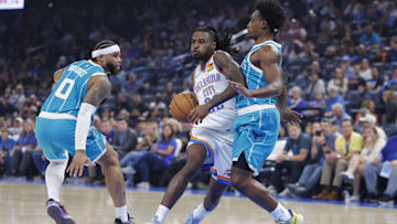 Oct 9, 2025; Oklahoma City, Oklahoma, USA; Oklahoma City Thunder guard Cason Wallace (22) drives down the court between Charlotte Hornets forward Miles Bridges (0) and guard Collin Sexton (8) during the second quarter of a game between the Charlotte Hornets and the Oklahoma City Thunder at Paycom Center. Mandatory Credit: Alonzo Adams-Imagn Images