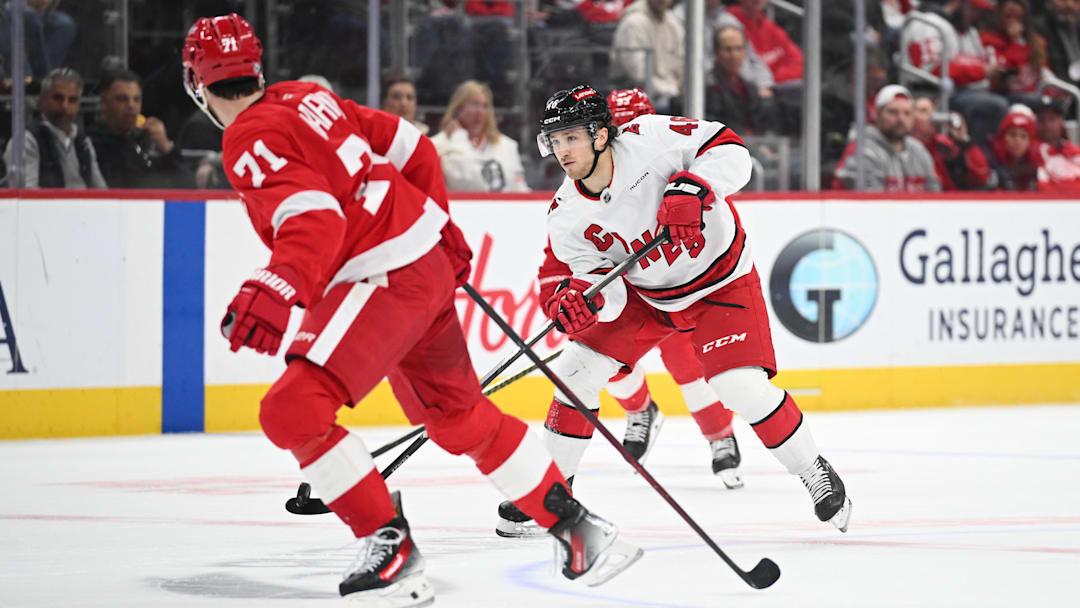 Apr 4, 2025; Detroit, Michigan, USA; Carolina Hurricanes center Justin Robidas (46) brings the puck up ice against Detroit Red Wings center Dylan Larkin (71) during the first period at Little Caesars Arena. Mandatory Credit: Tim Fuller-Imagn Images