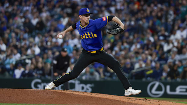 Seattle Mariners reliever Emerson Hancock throws a pitch off the mound, wearing a blue and yellow jersey and hat. 