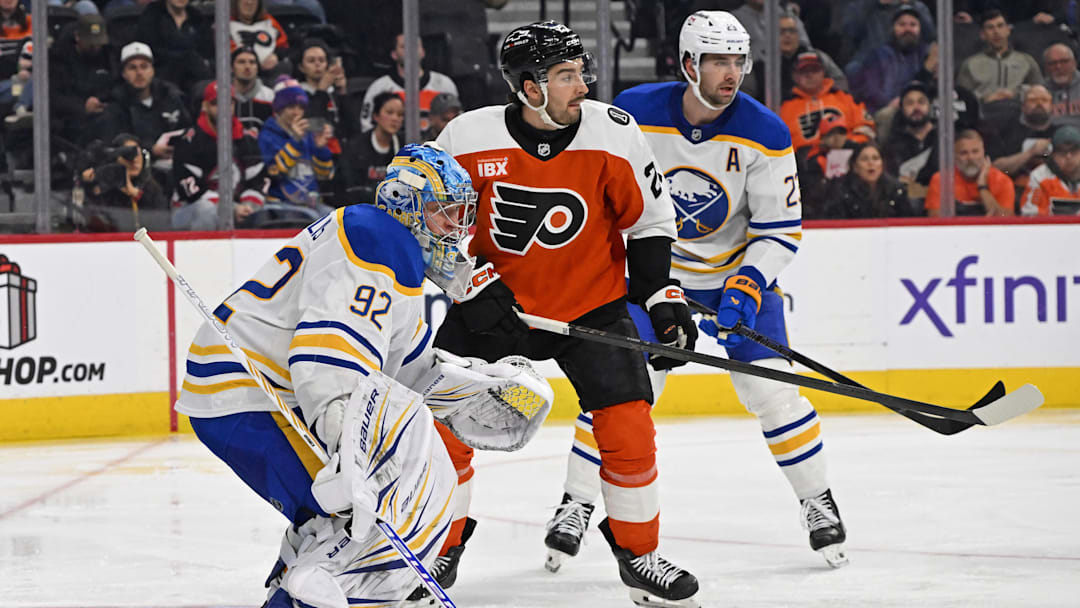 Dec 3, 2025; Philadelphia, Pennsylvania, USA; Philadelphia Flyers left wing Noah Cates (27) battle for the puck with Buffalo Sabres goaltender Colten Ellis (92) and defenseman Mattias Samuelsson (23) during the second period at Xfinity Mobile Arena. Mandatory Credit: Eric Hartline-Imagn Images