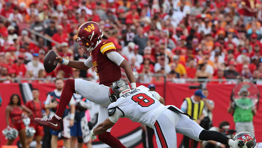 Sep 8, 2024; Tampa, Florida, USA;  Washington Commanders quarterback Jayden Daniels (5) runs past Tampa Bay Buccaneers linebacker SirVocea Dennis (8)  for a touchdown during the second half at Raymond James Stadium. Mandatory Credit: Kim Klement Neitzel-Imagn Images