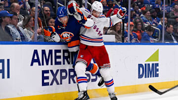 Apr 10, 2025; Elmont, New York, USA;  New York Rangers defenseman Braden Schneider (4) checks New York Islanders right wing Maxim Tsyplakov (7) into the boards during the second period at UBS Arena. Mandatory Credit: Dennis Schneidler-Imagn Images