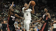 Oct 30, 2025; San Antonio, Texas, USA; San Antonio Spurs guard Stephon Castle (5) drives to the basket between Miami Heat forwards Andrew Wiggins (22) and Bam Adebayo (13) during the first half at Frost Bank Center. Mandatory Credit: Scott Wachter-Imagn Images