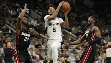 Oct 30, 2025; San Antonio, Texas, USA; San Antonio Spurs guard Stephon Castle (5) drives to the basket between Miami Heat forwards Andrew Wiggins (22) and Bam Adebayo (13) during the first half at Frost Bank Center. Mandatory Credit: Scott Wachter-Imagn Images