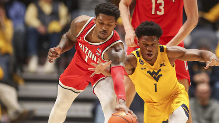 Jan 7, 2025; Morgantown, West Virginia, USA; Arizona Wildcats guard Caleb Love (1) and West Virginia Mountaineers guard Joseph Yesufu (1) fight for a loose ball during the first half at WVU Coliseum. Mandatory Credit: Ben Queen-Imagn Images