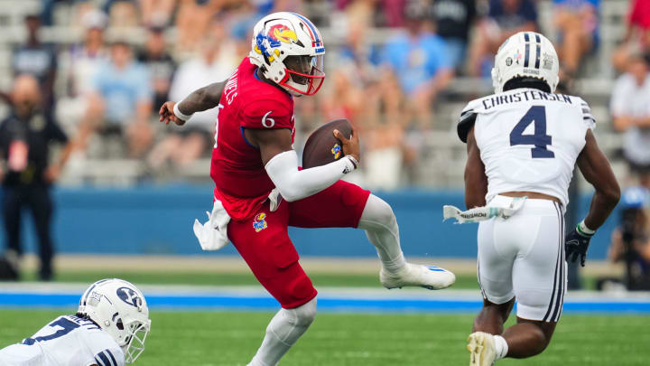 Sep 23, 2023; Lawrence, Kansas, USA; Kansas Jayhawks quarterback Jalon Daniels (6) runs the ball against Brigham Young Cougars cornerback Kamden Garrett (7) and cornerback Caleb Christensen (4) during the second half at David Booth Kansas Memorial Stadium. Mandatory Credit: Jay Biggerstaff-USA TODAY Sports