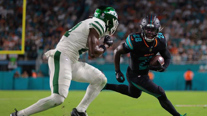 Sep 29, 2025; Miami Gardens, Florida, USA;  Miami Dolphins running back De'von Achane (28) rushes the ball against New York Jets cornerback Brandon Stephens (21) during the first half at Hard Rock Stadium. Mandatory Credit: Sam Navarro-Imagn Images