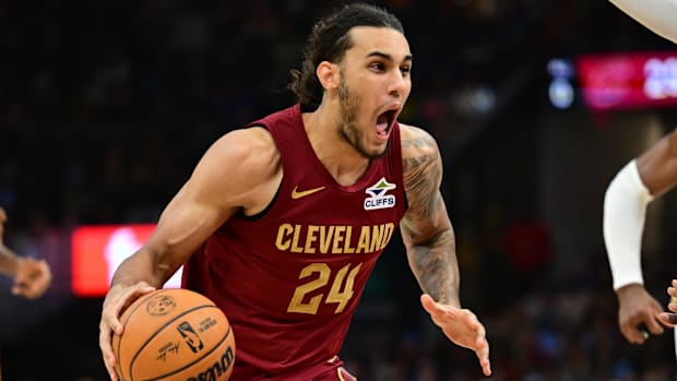 A basketball player dribbles a basketball while wearing a wine uniform.