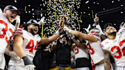 Ohio State Buckeyes head coach Ryan Day hoists the trophy as he celebrates with his players after defeating the Notre Dame Fighting Irish during the CFP National Championship college football game at Mercedes-Benz Stadium.
