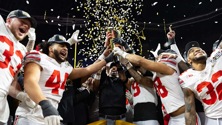 Ohio State Buckeyes head coach Ryan Day hoists the trophy as he celebrates with his players after defeating the Notre Dame Fighting Irish during the CFP National Championship college football game at Mercedes-Benz Stadium.