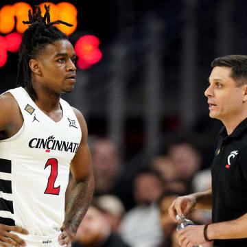 Cincinnati Bearcats head coach Wes Miller, right, talks with Cincinnati Bearcats guard Jizzle James (2) in the first half of a college basketball game against the Bradley Braves during a second-round game of the National Invitation Tournament,, Saturday, March 23, 2024, at Fifth Third Arena in Cincinnati.