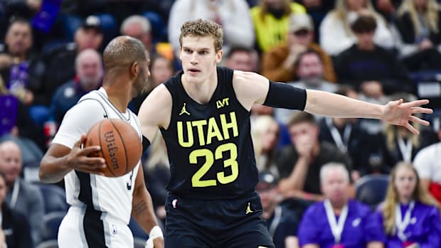 The goalkeeper of San Antonio Spurs Chris Paul (3) dribble the ball around Utah Jazz Forward / Center Lauri Markkanen (23) during the fir trees