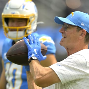 Sep 8, 2024; Inglewood, California, USA; Los Angeles Chargers head coach Jim Harbaugh catches the ball for quarterback Justin Herbert (10) as he warms up prior to the game against the Los Angeles Chargers at SoFi Stadium. Mandatory Credit: Jayne Kamin-Oncea-Imagn Images