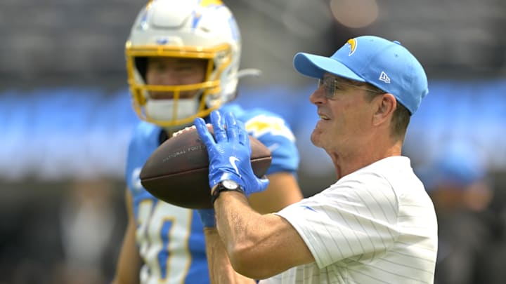 Sep 8, 2024; Inglewood, California, USA; Los Angeles Chargers head coach Jim Harbaugh catches the ball for quarterback Justin Herbert (10) as he warms up prior to the game against the Los Angeles Chargers at SoFi Stadium. Mandatory Credit: Jayne Kamin-Oncea-Imagn Images