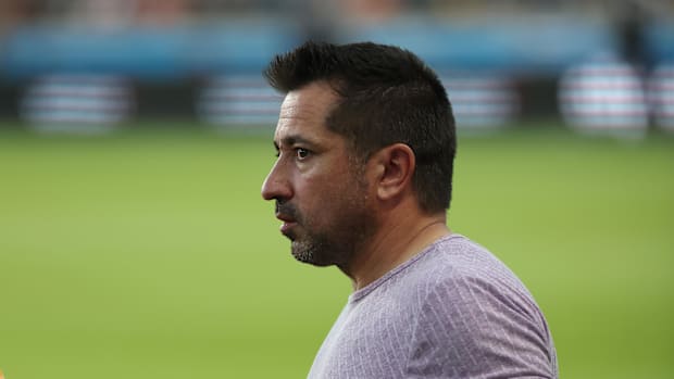 A close-up of former Houston Dash head coach Fran Alonso standing on a soccer pitch. 