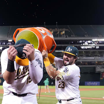 Sep 6, 2024; Oakland, California, USA; Oakland Athletics left fielder Seth Brown (center) reacts as right fielder Lawrence Butler (4) and catcher Shea Langeliers (23) dumps water and Gatorade after defeating the Detroit Tigers at Oakland-Alameda County Coliseum. Mandatory Credit: Darren Yamashita-Imagn Images