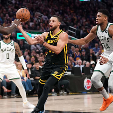 Golden State Warriors guard Stephen Curry (30) passes the ball between Milwaukee Bucks forward Bobby Portis (9) and forward Giannis Antetokounmpo (34) in the third quarter at the Chase Center. Mandatory Credit: Cary Edmondson-Imagn Images