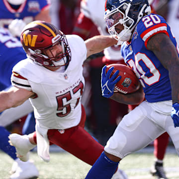 Nov 3, 2024; East Rutherford, New Jersey, USA; New York Giants cornerback Greg Stroman Jr. (30) returns a kickoff as Washington Commanders linebacker Nick Bellore (57) defends during the first half at MetLife Stadium. Mandatory Credit: Vincent Carchietta-Imagn Images