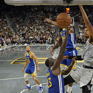 San Antonio Spurs forward Victor Wembanyama dunks over Golden State Warriors forward Draymond Green.