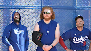 Feb 18, 2024; Glendale, AZ, USA;  Los Angeles Dodgers starting pitcher Tony Gonsolin (26), starting pitcher Dustin May (85) and relief pitcher Joe Kelly (99) lean on a fence in the bull pen during spring training at Camelback Ranch. Mandatory Credit: Jayne Kamin-Oncea-Imagn Images