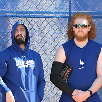 Feb 18, 2024; Glendale, AZ, USA;  Los Angeles Dodgers starting pitcher Tony Gonsolin (26), starting pitcher Dustin May (85) and relief pitcher Joe Kelly (99) lean on a fence in the bull pen during spring training at Camelback Ranch. Mandatory Credit: Jayne Kamin-Oncea-Imagn Images