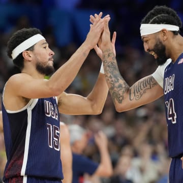 Jul 28, 2024; Villeneuve-d'Ascq, France; United States guard Devin Booker (15) and center Anthony Davis (14) celebrate in the fourth quarter against Serbia during the Paris 2024 Olympic Summer Games at Stade Pierre-Mauroy. Mandatory Credit: John David Mercer-USA TODAY Sports
