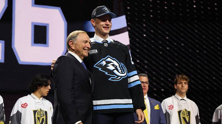 Jun 26, 2026; Buffalo, New York, USA; Ethan Belchetz reacts beside NHL commissioner Gary Bettman after being selected with the seventeenth pick in the first round of the 2026 NHL Draft by the Utah Mammoth at KeyBank Center. Mandatory Credit: Timothy T. Ludwig-Imagn Images