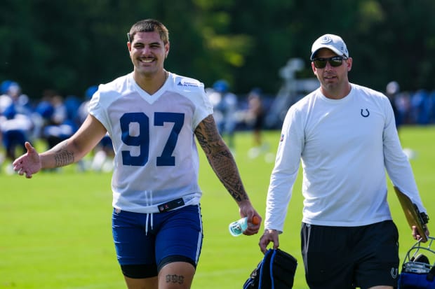 Football player Laiatu Latu smiles after practice in a white jersey.