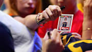 A fan hands a Caitlin Clark rookie card to Clark for signing before a game